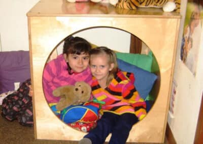 Two girls in a playhouse with stuffed toys