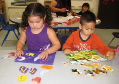Children doing puzzles at a classroom table.