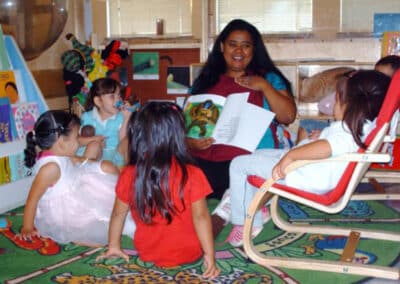 CCCDS staffer reading a book in story time to young children