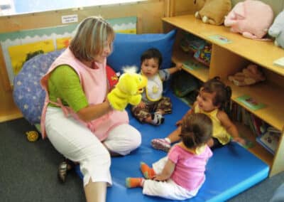 Teacher with puppet entertaining 3 babies