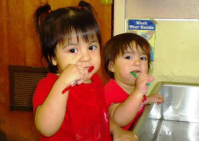 Two young children brushing their teeth at a sink.